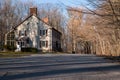 Old house with a chimney with shuttered windows in the park in the early spring. Road leading to the house