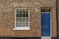 Old House FaÃ§ade with a Wooden Blue Door and Window on brick wall Royalty Free Stock Photo