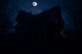 Old house with a Ghost in the forest at night or Abandoned Haunted Horror House in fog. Old mystic building in dead tree forest. Royalty Free Stock Photo