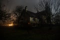 Old house with a Ghost in the forest at night or Abandoned Haunted Horror House in fog. Old mystic building in dead tree forest. Royalty Free Stock Photo