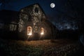 Old house with a Ghost in the forest at night or Abandoned Haunted Horror House in fog. Old mystic building in dead tree forest. Royalty Free Stock Photo