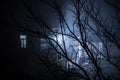 Old house with a Ghost in the forest at night or Abandoned Haunted Horror House in fog. Old mystic building in dead tree forest. Royalty Free Stock Photo