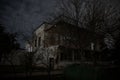 Old house with a Ghost in the forest at night or Abandoned Haunted Horror House. Old mystic building in dead tree forest. Surreal