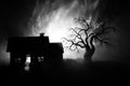 Old house with a Ghost at night with spooky tree or Abandoned Haunted Horror House in toned foggy sky with light. Old mystic build Royalty Free Stock Photo