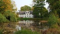 An old house and its reflection in the water of a reservoir in the Latvian village of Jaungulbene on October 2, 2020 Royalty Free Stock Photo