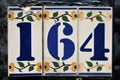 An old house number plate. Number 164.