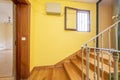 Old house with a staircase with wooden steps, wrought iron railing, yellow painted walls and a small storage room with a green Royalty Free Stock Photo