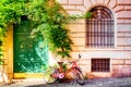 Old house wall in Trastevere, Rome, Italy with a red bicycle and green door. Old cozy street in Rome Royalty Free Stock Photo