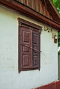 An old house with a white wall whose window is covered with wooden shutters Royalty Free Stock Photo