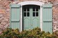 Old house with windows and green shutters. Traditional exterior of rural house, France. Facade of medieval stone building. Royalty Free Stock Photo