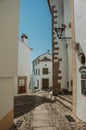 Old houses with whitewashed wall in cobblestone alley on slope