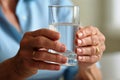 Old human hands close up grandmother holding glass of mineral water woman drinking fresh clear health pure refreshing Royalty Free Stock Photo