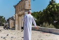 An old imam wearing white arabian gowns and feeding birds and cats at the Golden Dome of the Rock, an Islamic shrine located on