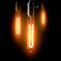 Old incandescent lamp, elongated shape. On a dark background. Creates a cosiness.