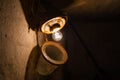 An old incandescent light bulb in an old rusty ceiling lamp in a dark basement close-up Royalty Free Stock Photo