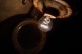 An old incandescent light bulb in an old rusty ceiling lamp in a dark basement close-up Royalty Free Stock Photo