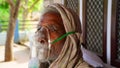 Old Indian man taking breathing from Oxygen supplier mask