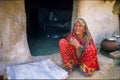 Old Indian woman crouching on the ground in front of her poor house. Rajasthan, Uttar Pradesh, India Royalty Free Stock Photo