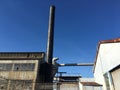 Old industrial buildings with metal smokestacks against a deep blue sky.