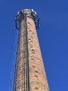 An old industrial chimney built of brick, reinforced with hoops, with built-in antennas against the blue sky Royalty Free Stock Photo