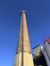 An old industrial chimney built of brick, reinforced with hoops, with built-in antennas against the blue sky Royalty Free Stock Photo