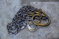Old industrial crane chain lays on concrete floor with rings and hooks
