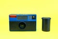 Old instamatic camera and its lens isolated on a yellow background