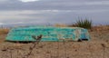 The old inverted green color boat lies on the sea shore in cloudy day Royalty Free Stock Photo