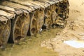 Old iron caterpillar in wet sand. Rusty steel wheels and caterpillar tape of a large bulldozer, tank, excavator, in damp sand and Royalty Free Stock Photo