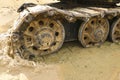 Old iron caterpillar in wet sand. Rusty steel wheels and caterpillar tape of a large bulldozer, tank, excavator, in damp sand and Royalty Free Stock Photo