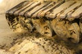 Old iron caterpillar in wet sand. Rusty steel wheels and caterpillar tape of a large bulldozer, tank, excavator, in damp sand and Royalty Free Stock Photo