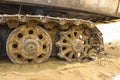 Old iron caterpillar in wet sand. Rusty steel wheels and caterpillar tape of a large bulldozer, tank, excavator, in damp sand and Royalty Free Stock Photo