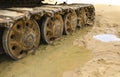 Old iron caterpillar in wet sand. Rusty steel wheels and caterpillar tape of a large bulldozer, tank, excavator, in damp sand and Royalty Free Stock Photo