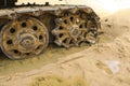 Old iron caterpillar in wet sand. Rusty steel wheels and caterpillar tape of a large bulldozer, tank, excavator, in damp sand and Royalty Free Stock Photo