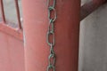 Old iron chain hanging on a red metal pipe Royalty Free Stock Photo