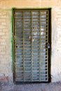 An old iron door with a grating in the white brick wall Royalty Free Stock Photo