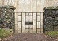 Old iron gate in old stone wall in front of misty forest. Royalty Free Stock Photo