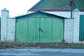 Old iron green garage and gray brick fence Royalty Free Stock Photo