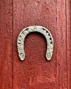 Old iron horseshoe on a wooden red painted door background. Royalty Free Stock Photo