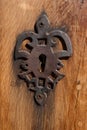 Old iron keyhole on a wooden door. Fleur-de-lis shape