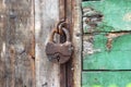 A old iron padlock hangs on the wood door. Locked door to the premise. Concept of protection, incarceration, protection