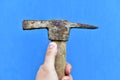 Old iron pickaxe in hand on a blue background