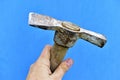 Old iron pickaxe in hand on a blue background