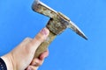 Old iron pickaxe in hand on a blue background