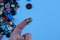 Iron thimble on finger against the background of colored buttons on the table