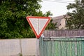 Old triangular road sign near a wooden fence