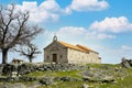 Old granite chapel in the countryside close to a deciduous tree