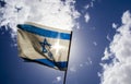 Old Israeli flag on blue sky and white clouds
