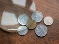 Old Italian Lira coins under magnifying glass on a wooden table. Local currencies that ceased to exist