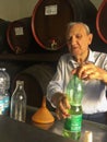 An old Italian man , taking pride in his wine made by himself and his family, sold in a recycled plastic bottle